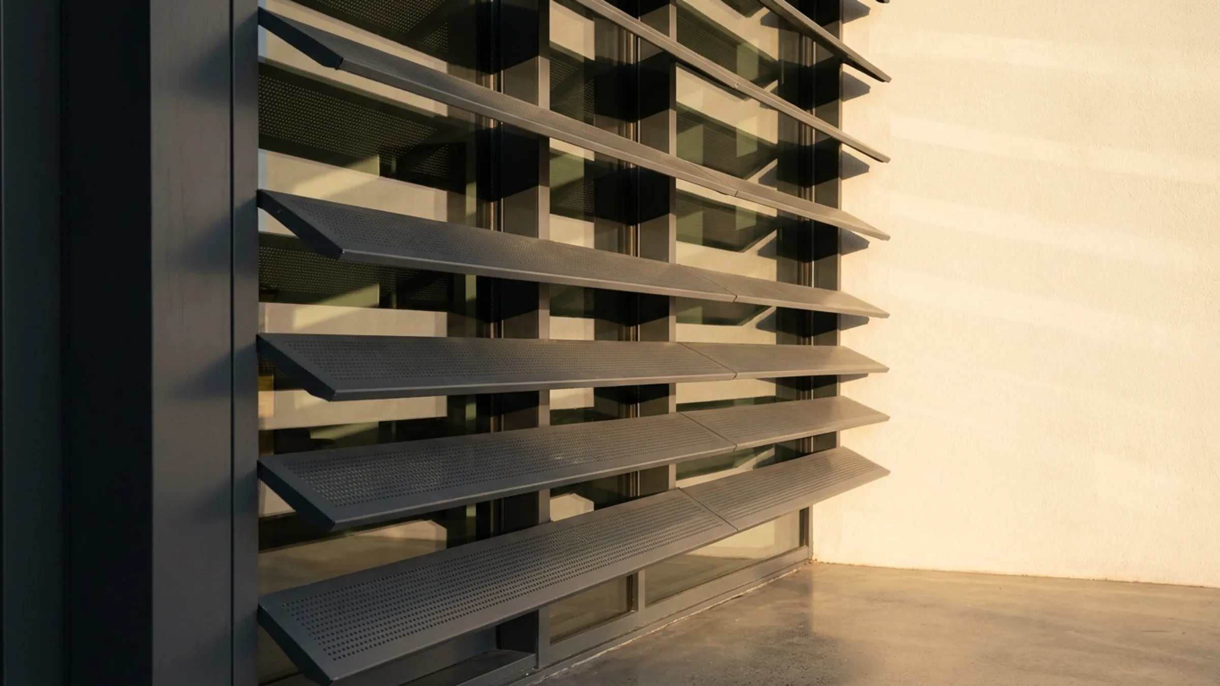 Aluminium brise soleil louvres shading a building facade in late afternoon light